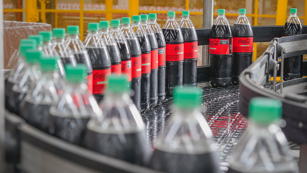 Botellas de Coca-Cola retornable en fila en línea de producción