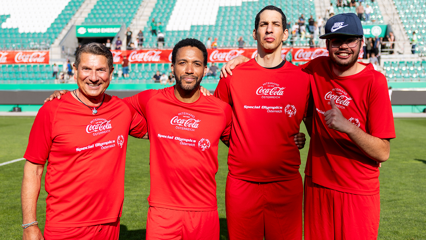 Cesar Sampson posiert mit drei Spielern beim Wiener Inklusionsderby 2025 im Allianz Stadion. Alle tragen rote Trikots mit den Logos von Coca-Cola und Special Olympics Österreich.