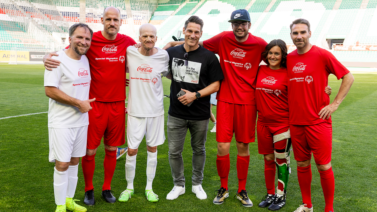 Helge Payer Sampson posiert mit Spielern beim Wiener Inklusionsderby 2025 im Allianz Stadion. Alle tragen rote oder weiße Trikots mit den Logos von Coca-Cola und Special Olympics Österreich.