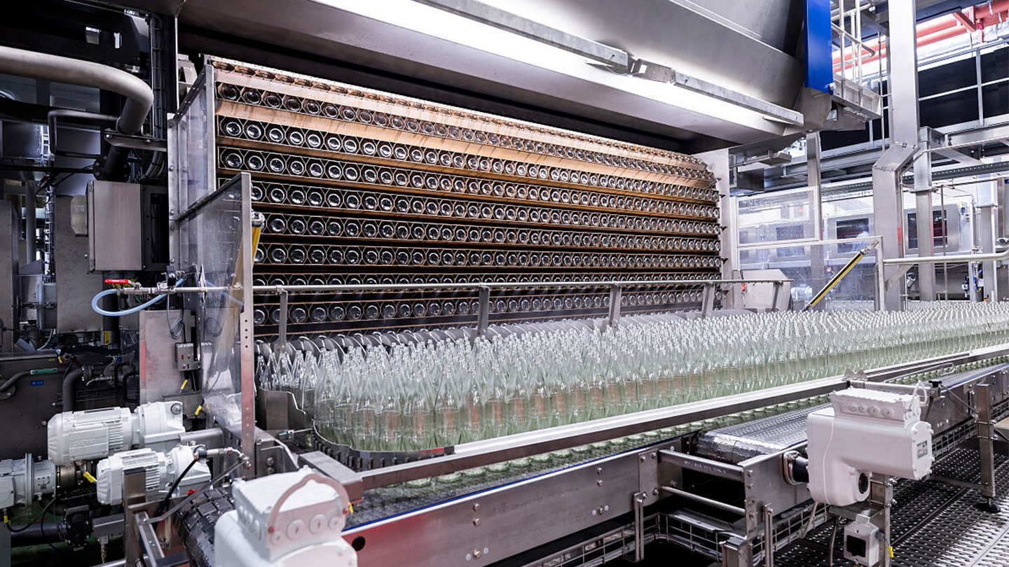 Viele Glasflachen auf einer modernen wassersparenden Waschanlage für Mehrwegflaschen in einem Produktionsgebäude