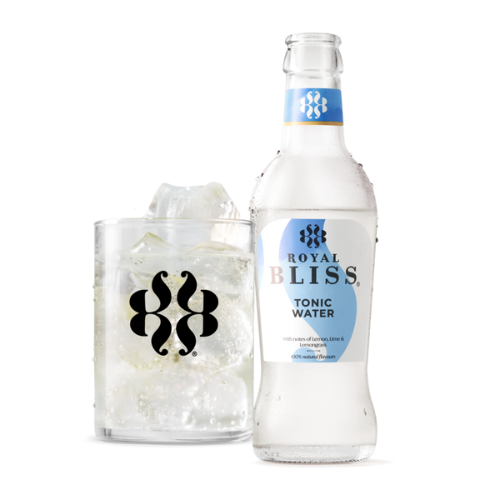 Fles “ROYAL BLISS – Tonic Water” met heldere, bruisende drank, blauw-wit etiket en zwart gestileerd logo. Tekst: “With notes of lemon, lime & lemongrass – 100% natural flavours”. Links een glas gevuld met alleen heldere bruisdrank en grote ijsblokjes, zonder fruit of extra decoratie.
