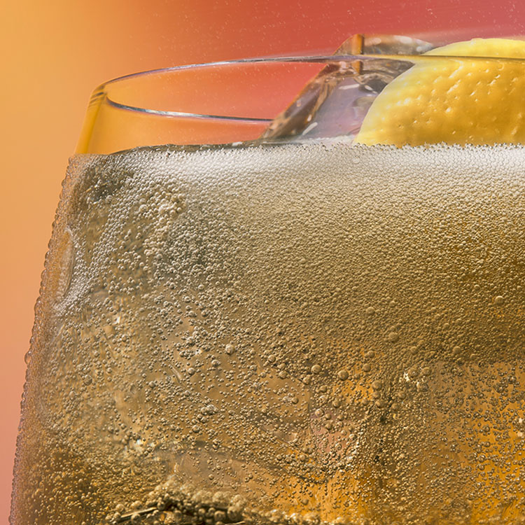 Close-up de uma bebida gelada de bubble tea soda em um copo com condensação, contendo cubos de gelo e uma fatia de limão, contra um fundo vermelho quente.