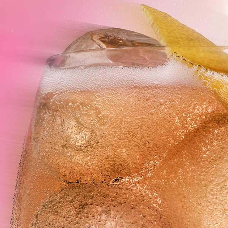 Um Fizzy Peach soda gelado, decorado com uma rodela de limão, em um close irresistível sobre um fundo rosa vibrante.