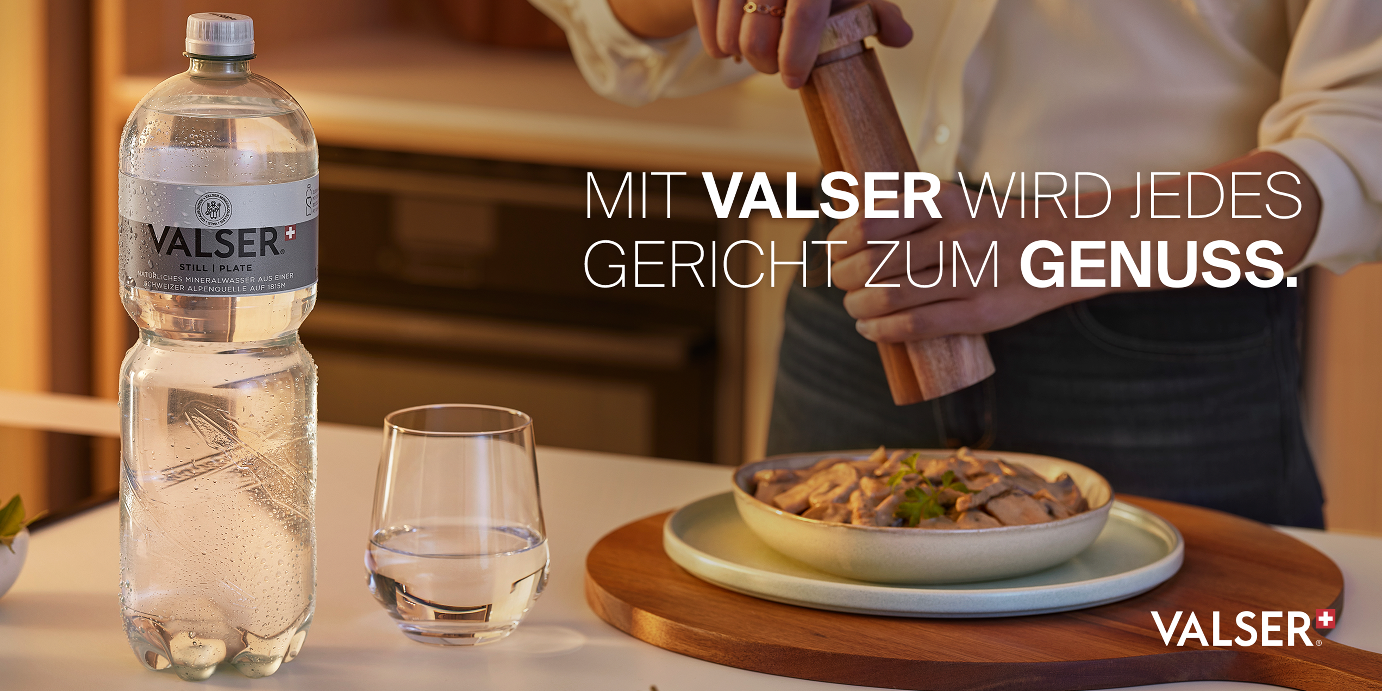 Valser-Flasche auf dem Tisch mit Wasserglas und Teller