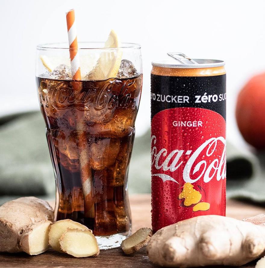 Photo d’une canette de Coca-Cola Zero Ginger avec un verre rempli de Coca-Cola Zero Ginger et des racines de gingembre.