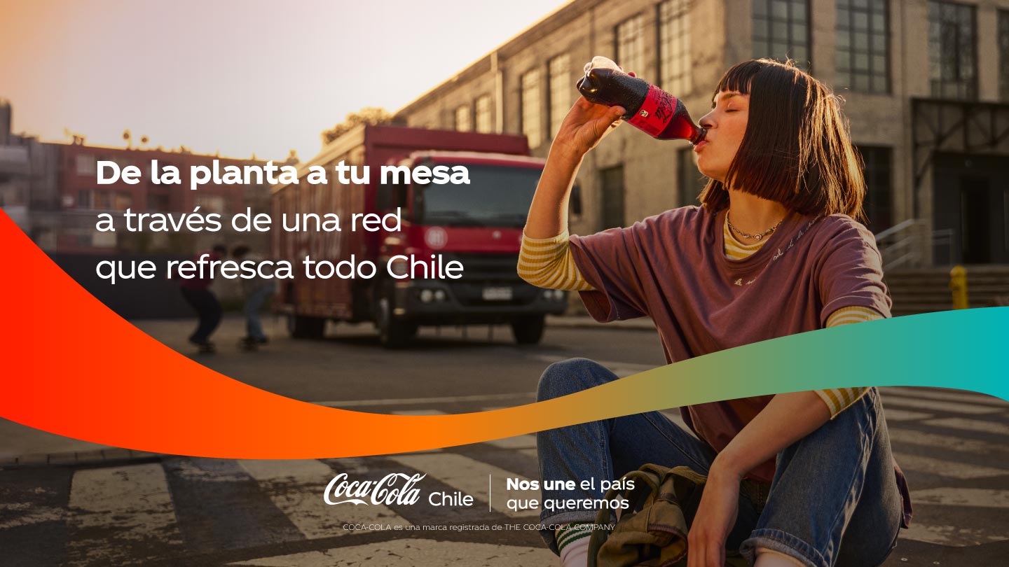 Mujer joven sentada en la calle, bebiendo una Coca-Cola, con un camión de reparto al fondo.