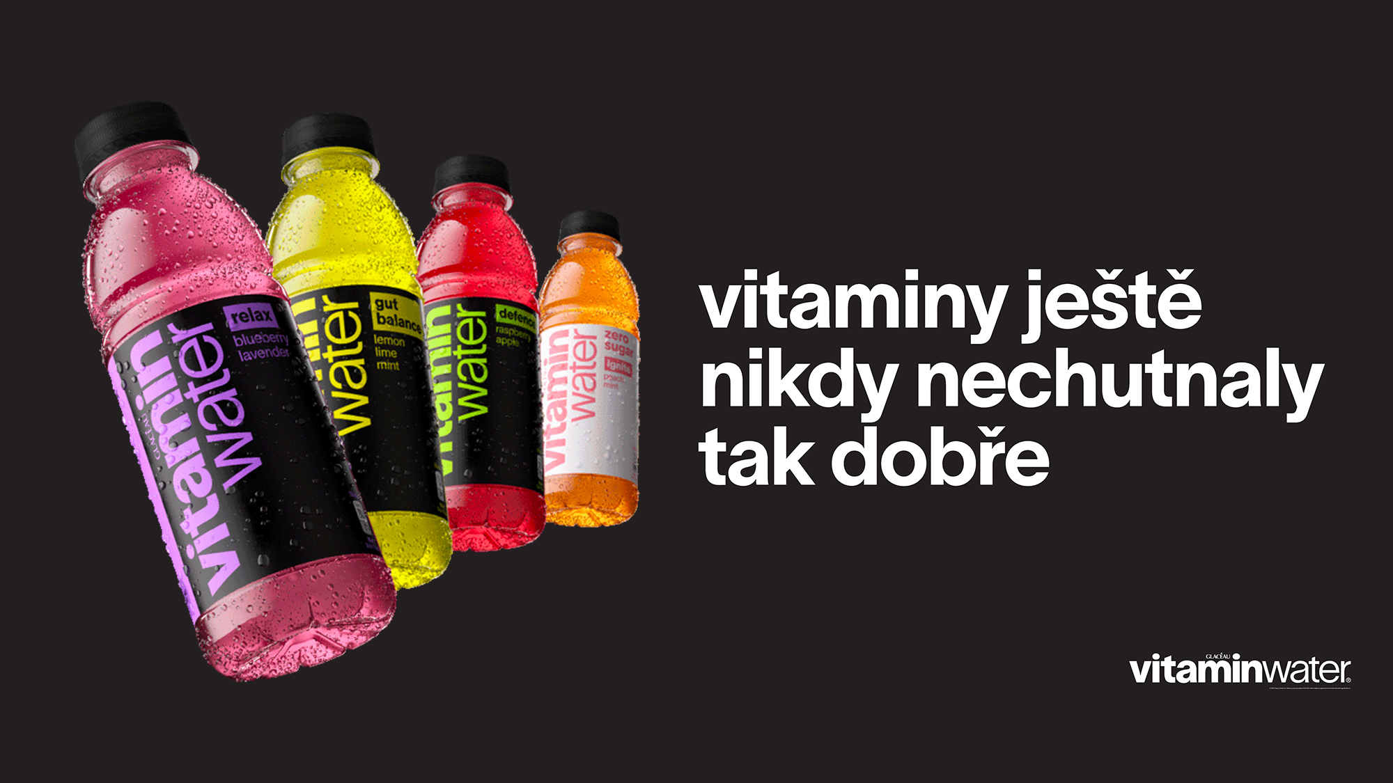 Barevné láhve vitaminwater různých příchutí na černém pozadí s textem o chutných vitamínech.