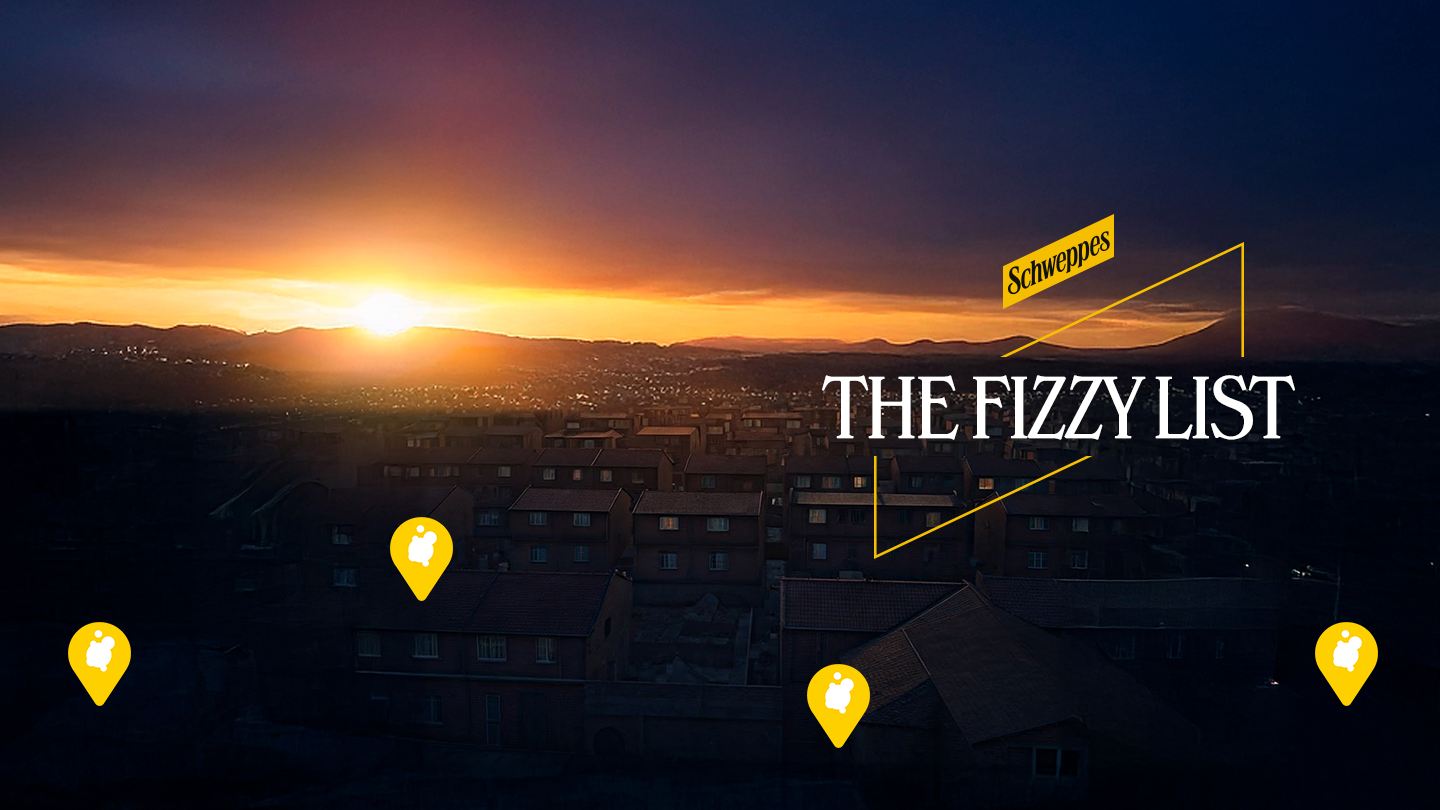 Заход сонца над горадам з лагатыпам Schweppes і надпісам The Fizzy List