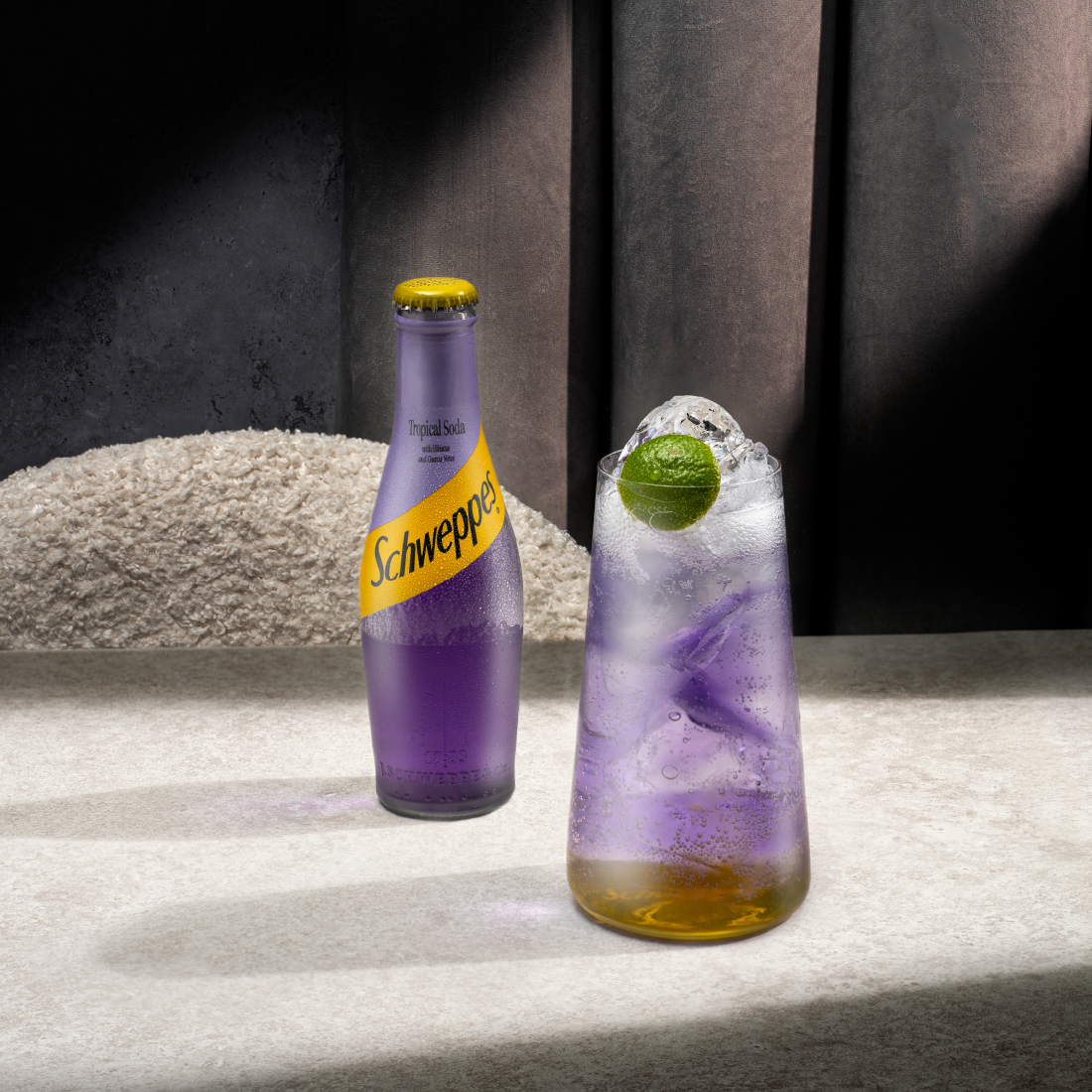 schweppes tropical soda bottle with a glass of tropical spritz on a table