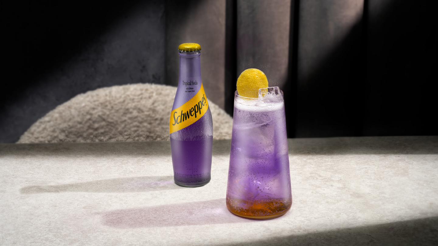 schweppes tropical soda bottle with a glass of tropical spritz on a table