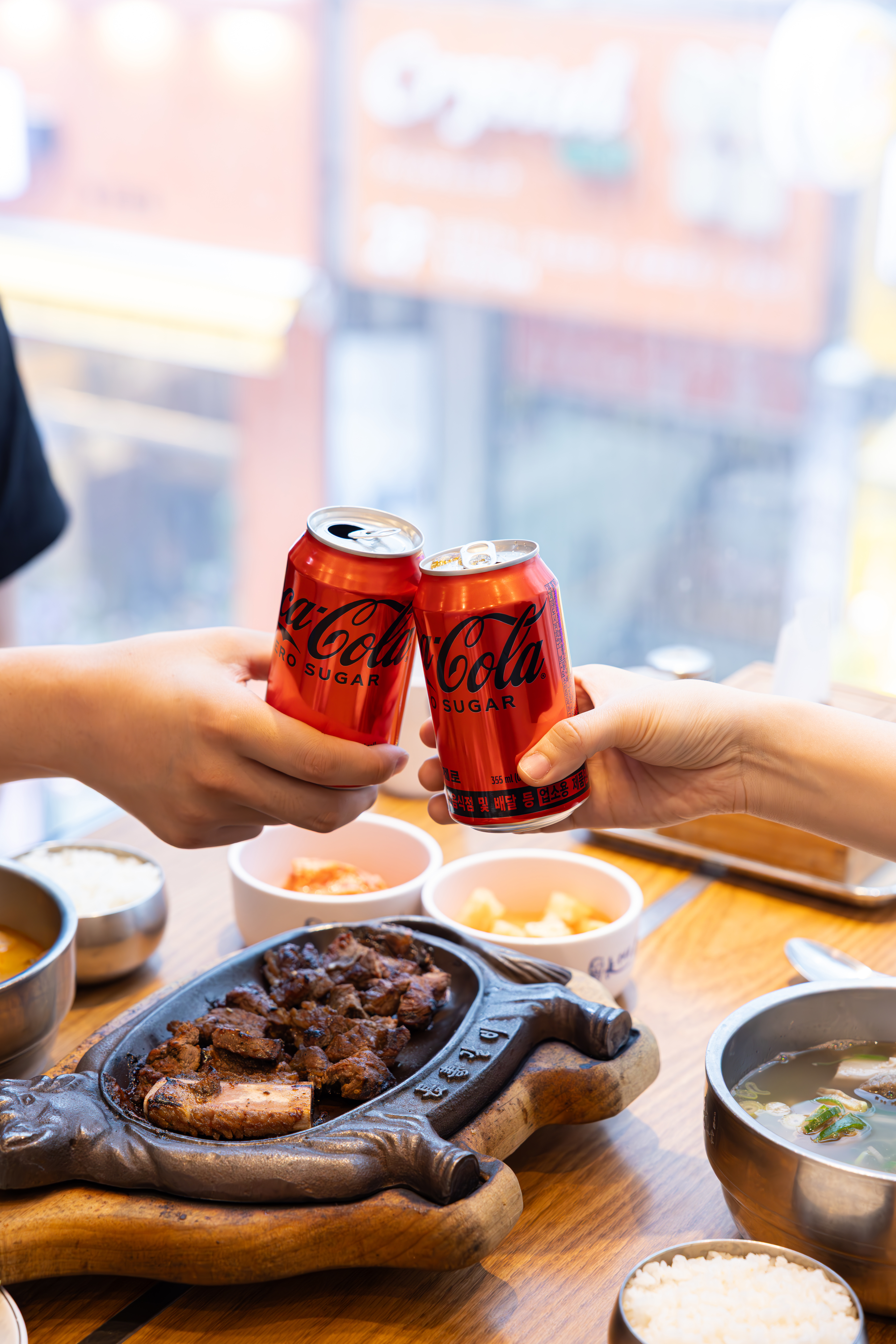 장수갈비집본가의 대표 메뉴들과 코카-콜라 제로 캔을 따고 있는 사진