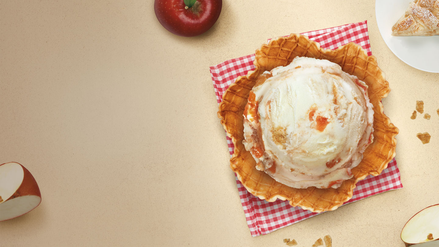Helado de strudel de manzana de Santa Clara Mexico en una cesta de barquillo, con manzanas rojas y migas de strudel de fondo.