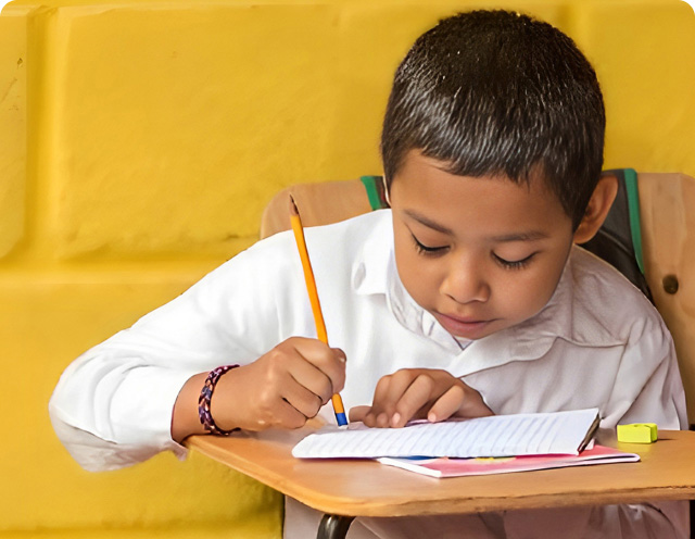 Niño de guardapolvo blanco estudiando en la escuela.