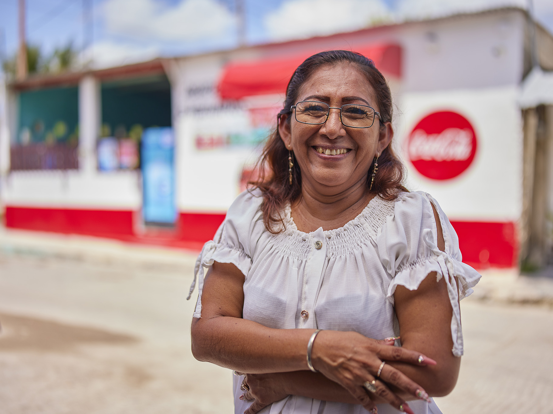 Imagen de una señora en primer plano y en el fondo un logo de Coca-Cola.
