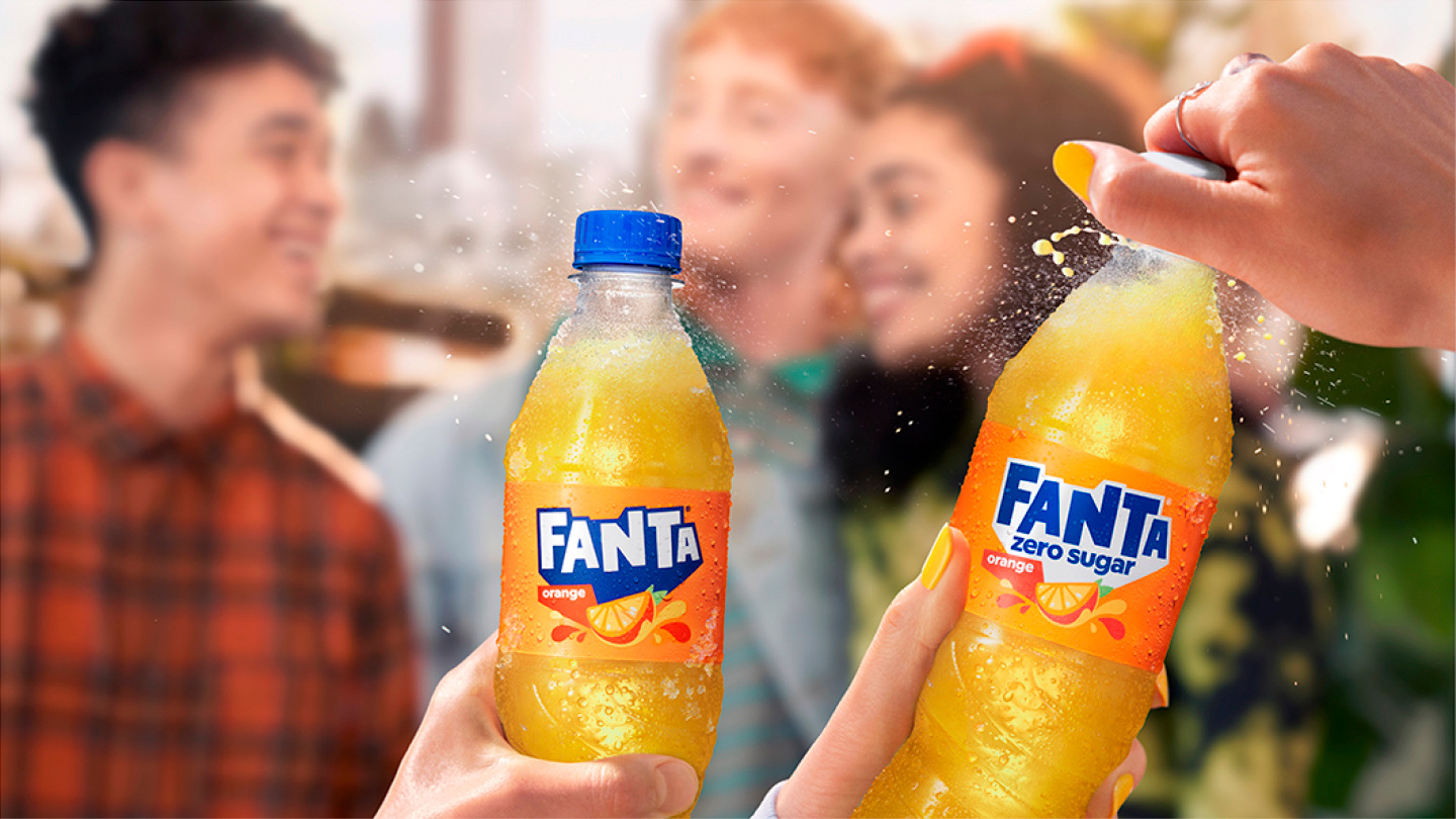 Dve rashlađene boce Fanta napitka, jedna klasična i jedna zero sugar, pri čemu se druga upravo otvara i ispušta kapljice osvežavajućeg soka