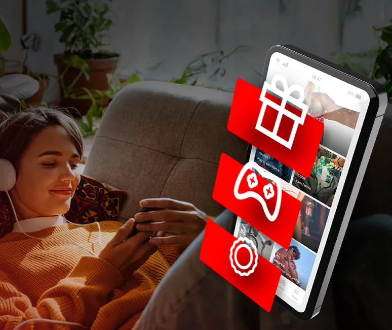 Person som ligger på en soffa med hörlurar bredvid en stor grafik av en telefon med app‑ikoner