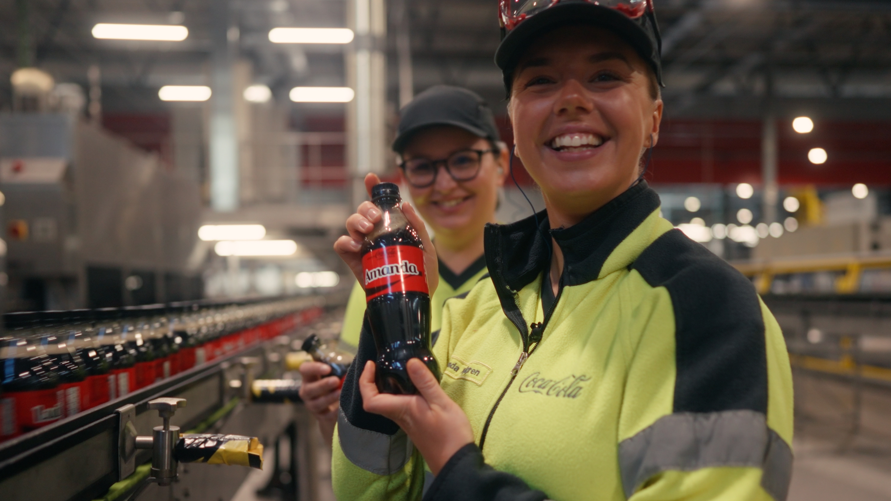 Hand som placerar en plastflaska i en röd returmaskin för återvinning.