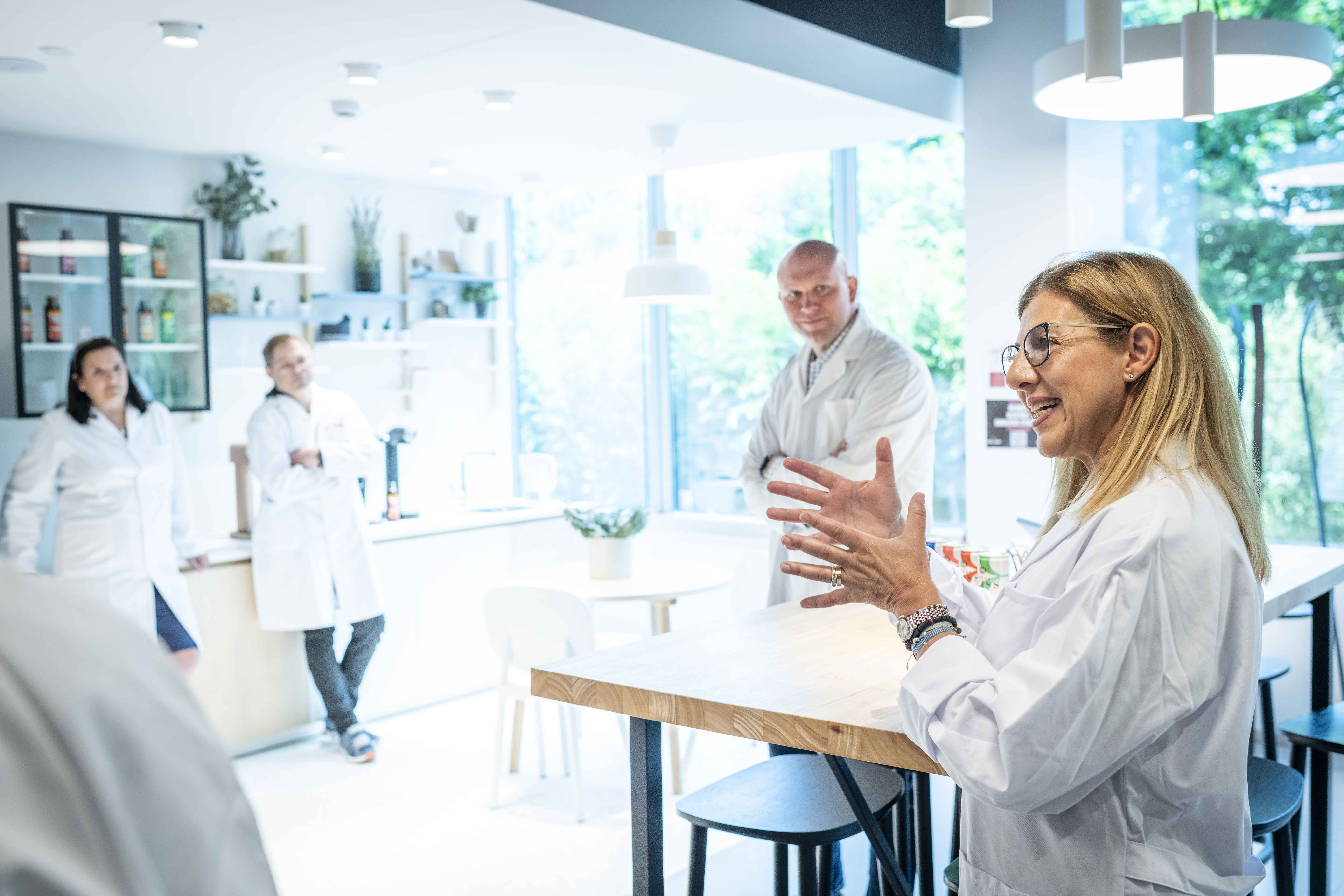Personer i labbrockar som har en diskussion i en ljus, modern laboratoriemiljö.